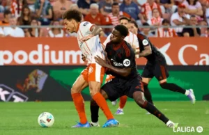 Agoumé pugna por un balón con Witsel en el Sevilla - Girona
