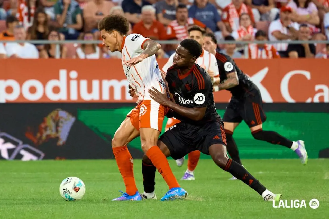 Agoumé pugna por un balón con Witsel en el Sevilla - Girona