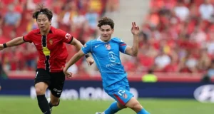 Takuma Asano pugna por un balón con Julián Álvarez en la temporada 25 26